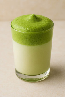 Matcha Latte. Honigmilch mit grünem Matchaschaum zum Einrühren
