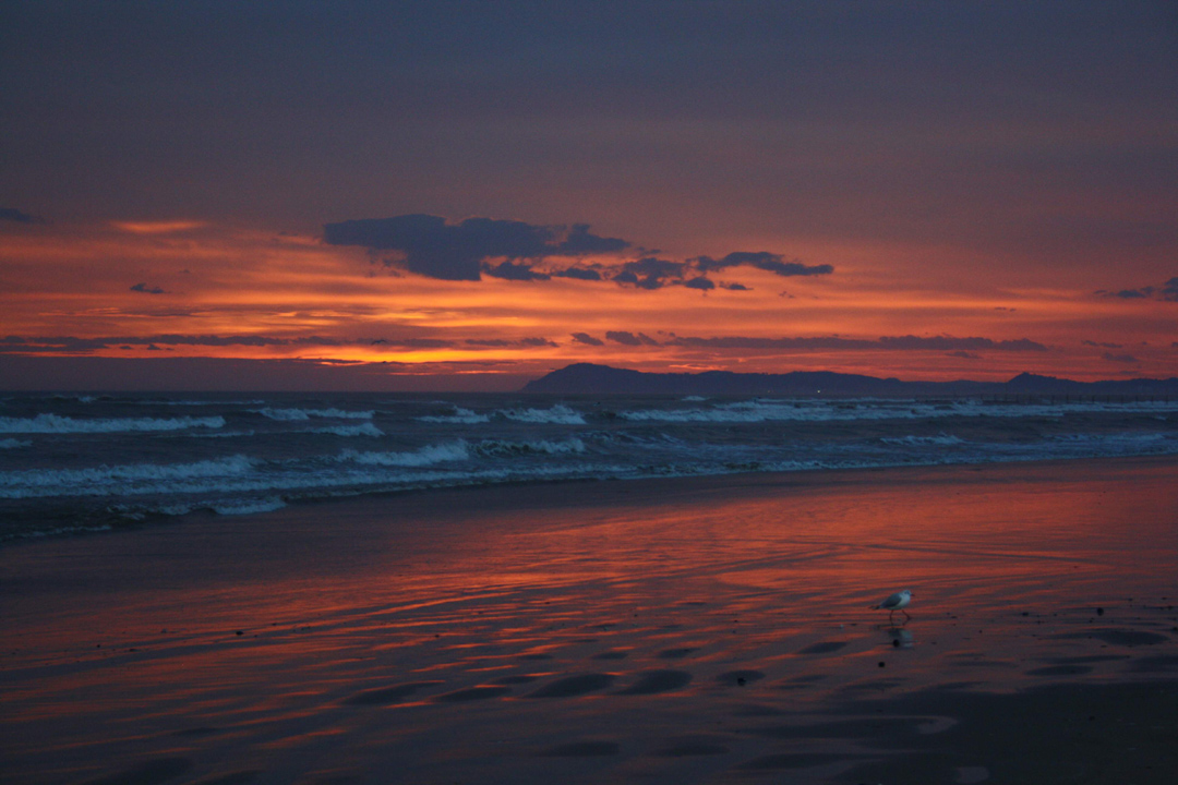 Außergewöhnliche Bilder. 17.1.2015 Vor dem Sonnenaufgang am Strand von Rimini am Meer mit Wellen und einigen Wolken am rot orangen Winterhimmel.