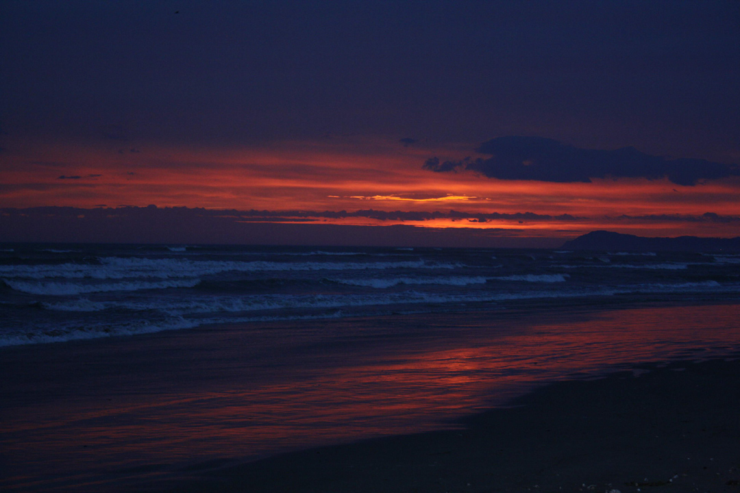Außergewöhnliche Bilder. 17.1.2015 Vor dem Sonnenaufgang am Strand von Rimini am Meer mit Wellen und einigen Wolken am rot orangen Winterhimmel.